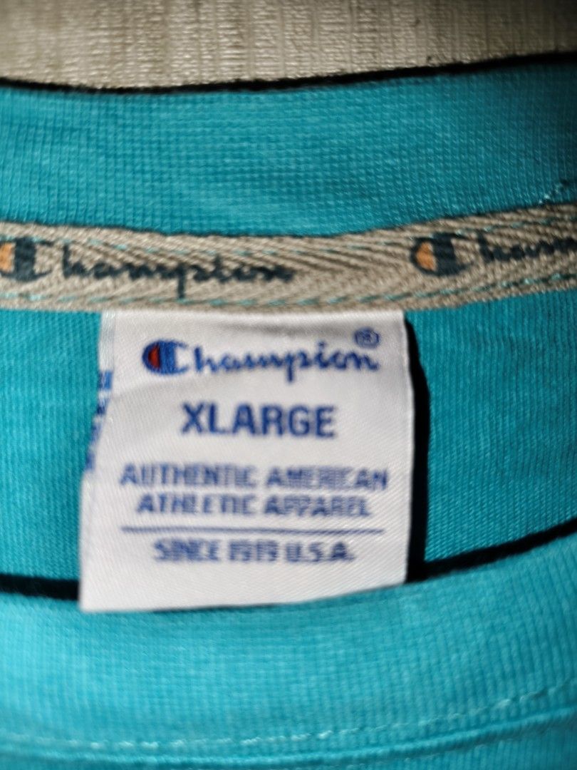 Champion Teal Script Logo T-Shirt XL (Category: Tshirts & Polo Shirts ) located in Baguio. Submitted by fordaluvofthrift2600 (Listing ID 1466169436, Image 2). Description: - Brand: Champion - Color: Teal - Size: M FIT TO L - Fit: Relaxed fit with short sleeves - Design: White cursive script logo embroidered on chest - Details: Small 'C' patch on left sleeve and woven label near bottom hem - Authenticity: Includes inner size tag and Champion Europ