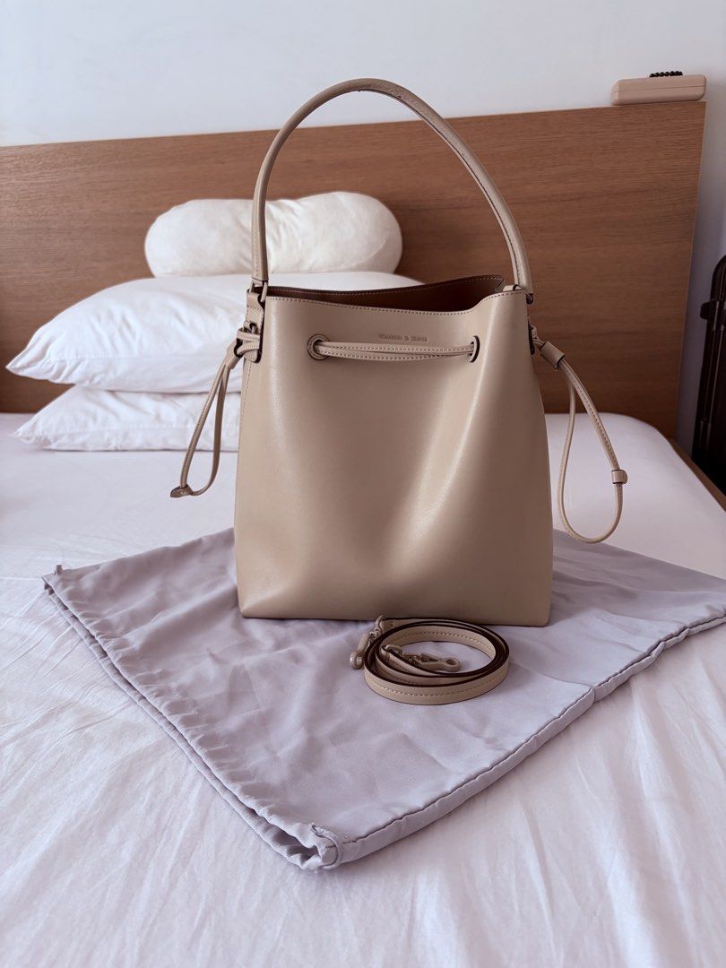 MUST GO! Charles & Keith Beige Bucket Bag with Strap (Category: Cross-body Bags) located in Las Pinas. Submitted by sabs28 (Listing ID 1466197393, Image 1). Description: Clean structured shape, drawstring closure across the top. Detachable matching strap included along with dust bag. Interior has a spacious brown lining with a reinforced base. Handle has minor scuffs, top and below. Flaws shown in pics. ** with dust bag and paper bag ** retails a