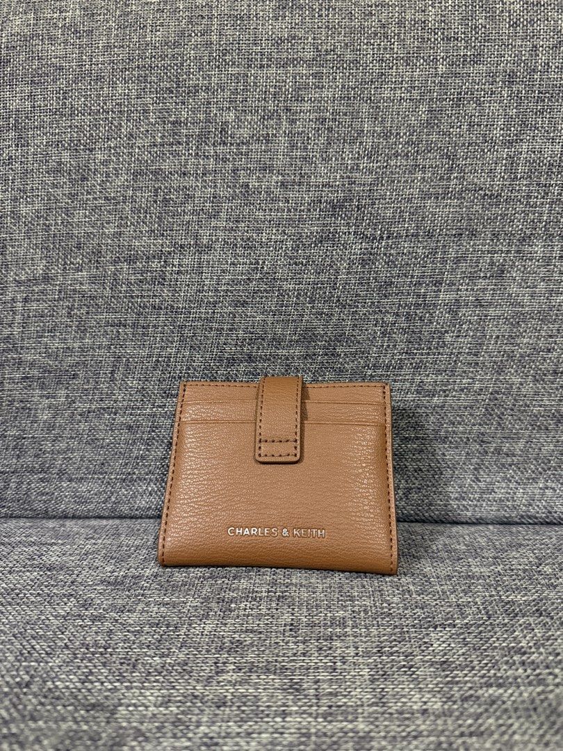 Charles & Keith Brown Card Holder Wallet (Category: Wallets & Card holders) located in Manila. Submitted by hannabananahhh (Listing ID 1466286969, Image 1). Description: - Brand: Charles and Keith - Material: Brown faux leather - Closure: Snap button on the back flap - Storage: Multiple card slots on front, back, and inside - Size: Compact and pocket-friendly - Condition: Clean inside and out with minimal signs of handling.