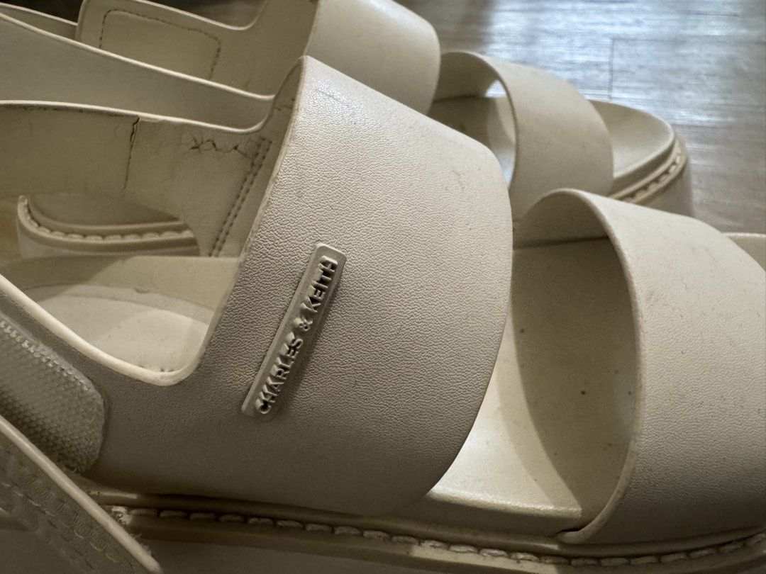 Charles & Keith White Platform Sandals (Category: Sandals) located in Pasig City. Submitted by prelovedby_alexx (Listing ID 1466214023, Image 2). Description: - Brand: Charles & Keith - Color: Creamy off-white - Sole: Chunky lug platform for added height and comfort - Design: Double strap with small metal brand logo plate - Fit: Adjustable velcro back strap - Style: Casual, easy slip-on everyday wear Issues: slight cracking of the leather as seen