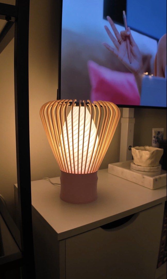 Chase Matcha Whisk Table Lamp (Category: Lighting) located in Taguig. Submitted by mfaithr (Listing ID 1466298295, Image 3). Description: - Unique matcha whisk/chasen lamp - Pink cylindrical base with a beige outer cage and swirled white inner bulb - Emits a cozy, warm, white, and natural glow when turned on - Standard wall plug-in - Compact size, fits nicely on your matcha corner.