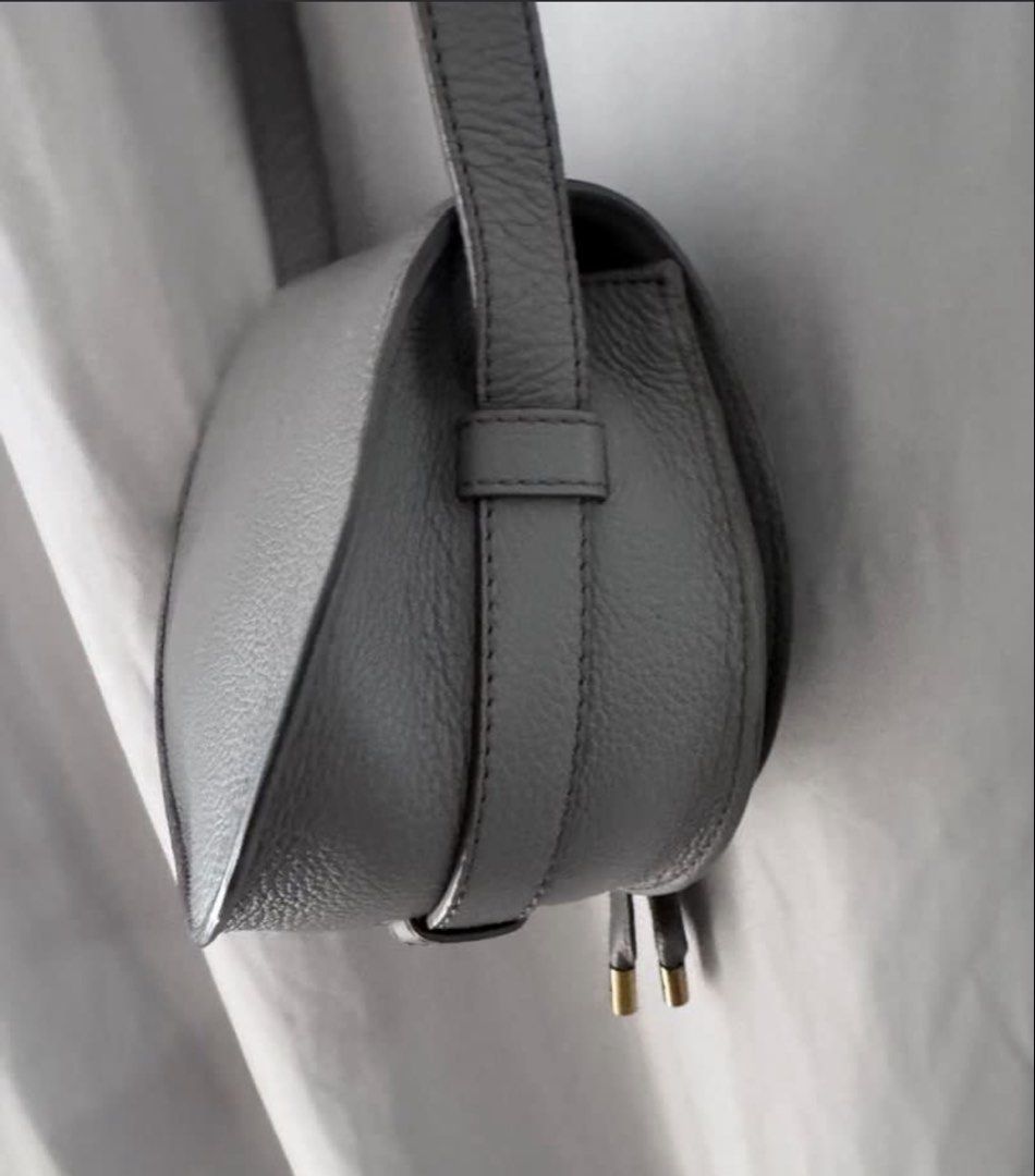 Chloé Marcie Saddle Bag Grey (Category: Luxury Bags & Wallets) located in Manila. Submitted by decluterthings888 (Listing ID 1466335614, Image 3). Description: Chloé Marcie saddle bag in a soft grey shade. Textured calfskin leather, horseshoe stitch detailing on the flap, antique gold hardware. Adjustable crossbody strap. Front flap closure with slip pocket underneath. Comes with original white dust bag and branded card. Clean interior and exteri