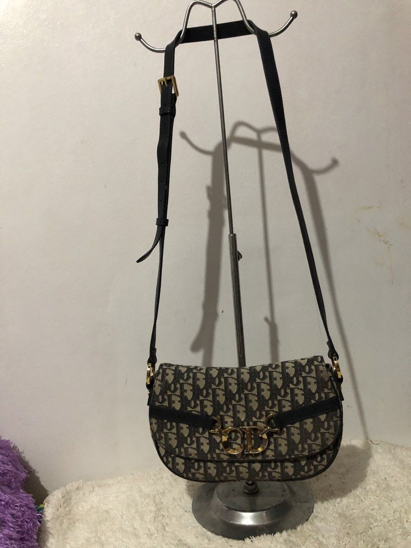 Christian Dior Oblique Saddle Shoulder Bag (Category: Luxury Bags & Wallets) located in Quezon City. Submitted by yunajohan24 (Listing ID 1466250879, Image 1). Description: - Brand: Christian Dior - Style: Saddle Shoulder Bag - Material: Blue and beige Oblique canvas with dark blue leather trim - Hardware: Gold-tone with iconic CD monogram closure - Interior: Black fabric lining with a convenient zippered pocket - Strap: Matching dark blue leathe