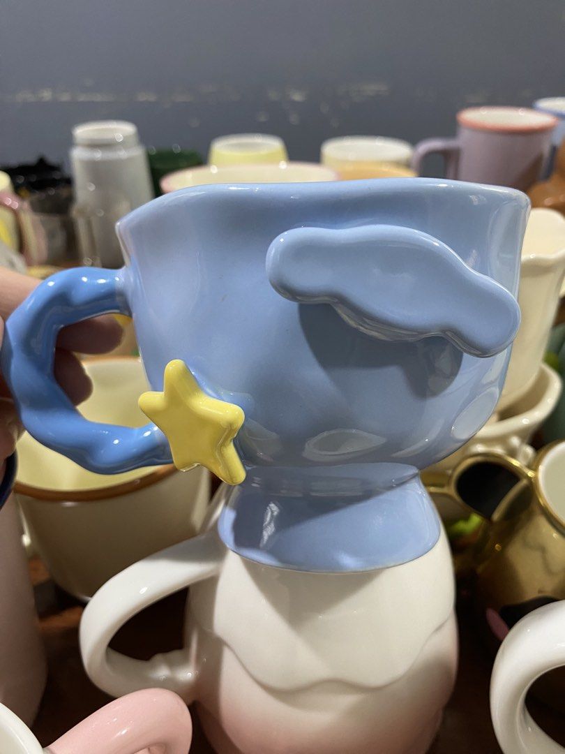 Cinnamoroll ceramic mug (Category: Coffee & Tea Tableware) located in Cavite. Submitted by catherinesanchez0817 (Listing ID 1466324239, Image 1). Description: - Color: Pastel blue with a glossy finish - Design: Unique sculpted cloud shape and attached yellow star near the handle - Base: Raised pedestal base - Material: High-quality ceramic - Perfect for daily use or as a cute desk display/gift.