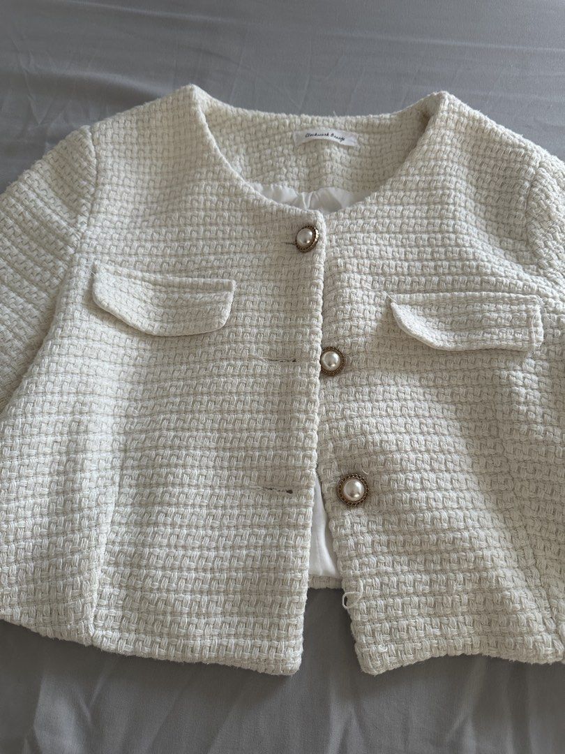 Clockwork Orange White Tweed Crop Jacket (Category: Coats, Jackets and Outerwear) located in Paranaque City. Submitted by declutterwyae (Listing ID 1466239169, Image 1). Description: - Brand: Clockwork Orange - Color: White - Material: Textured woven tweed fabric, fully lined - Design: Classic round neckline, long sleeves - Closure: Front fastening with 3 faux-pearl gold-rimmed buttons - Pockets: Two chest flap pockets.