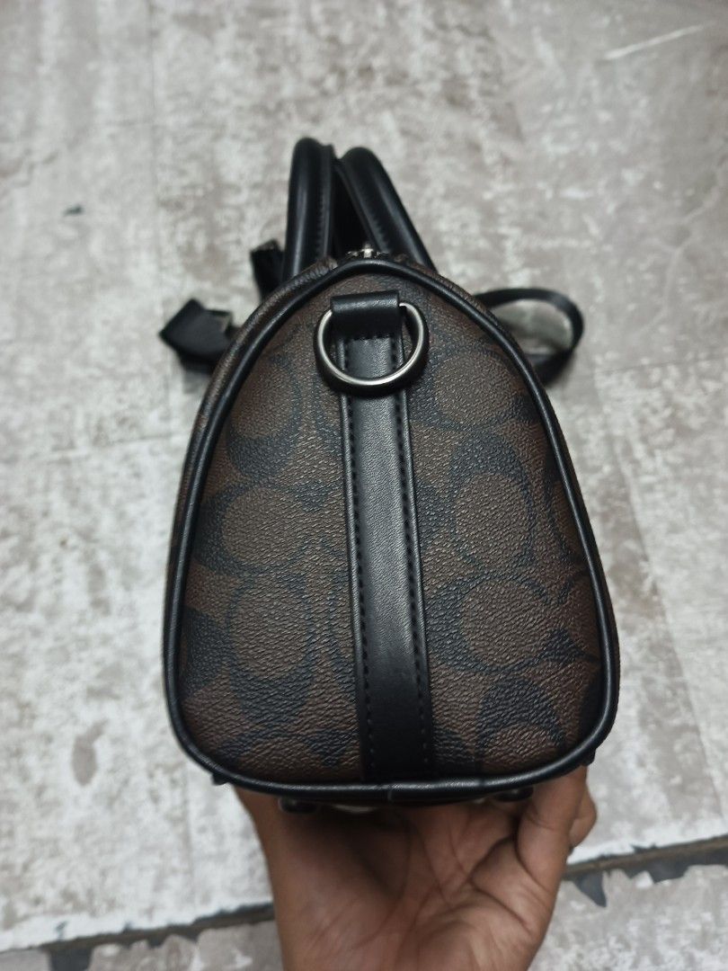 Coach Compass Bag 25 (Category: Cross-body Bags) located in Baguio. Submitted by brandeditems16 (Listing ID 1466324298, Image 2). Description: - Authentic Coach barrel bag - Brown signature canvas with sleek black leather trim - Dual top handles and secure top zip closure - Interior fabric lining with Coach creed patch and serial number C8929 - Includes a detachable black nylon shoulder strap for versatile wear - Comes with the iconic hanging lea