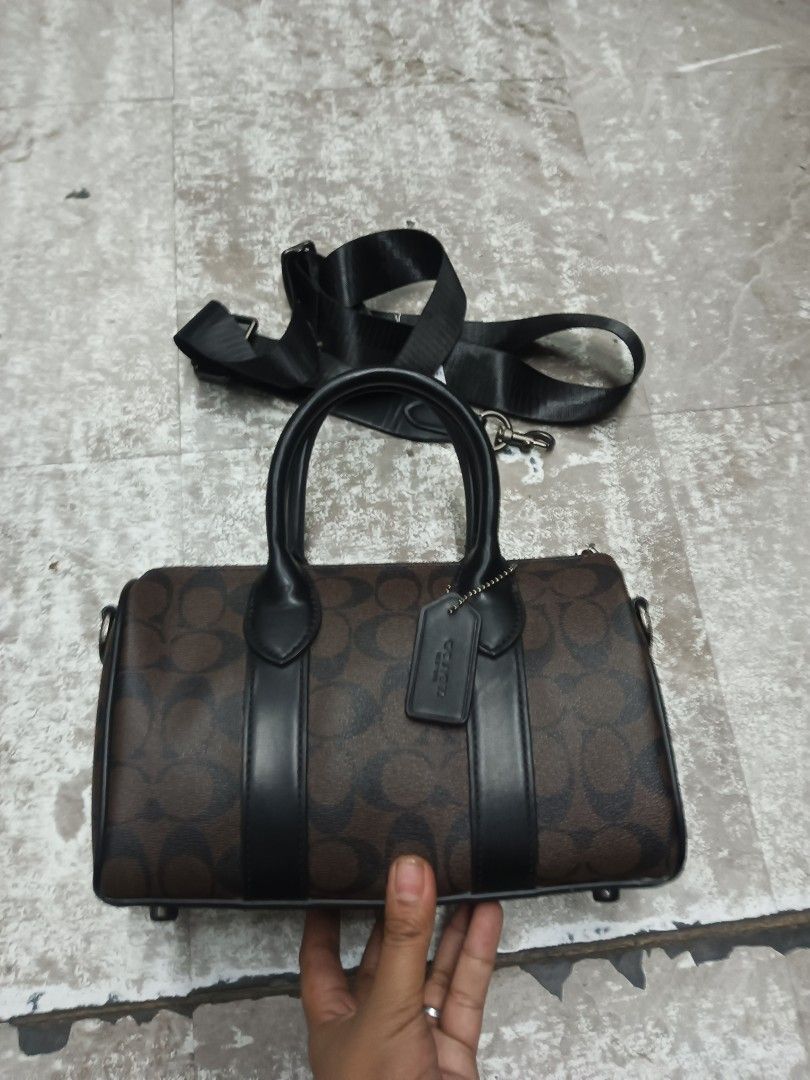 Coach Compass Bag 25 (Category: Cross-body Bags) located in Baguio. Submitted by brandeditems16 (Listing ID 1466324298, Image 1). Description: - Authentic Coach barrel bag - Brown signature canvas with sleek black leather trim - Dual top handles and secure top zip closure - Interior fabric lining with Coach creed patch and serial number C8929 - Includes a detachable black nylon shoulder strap for versatile wear - Comes with the iconic hanging lea