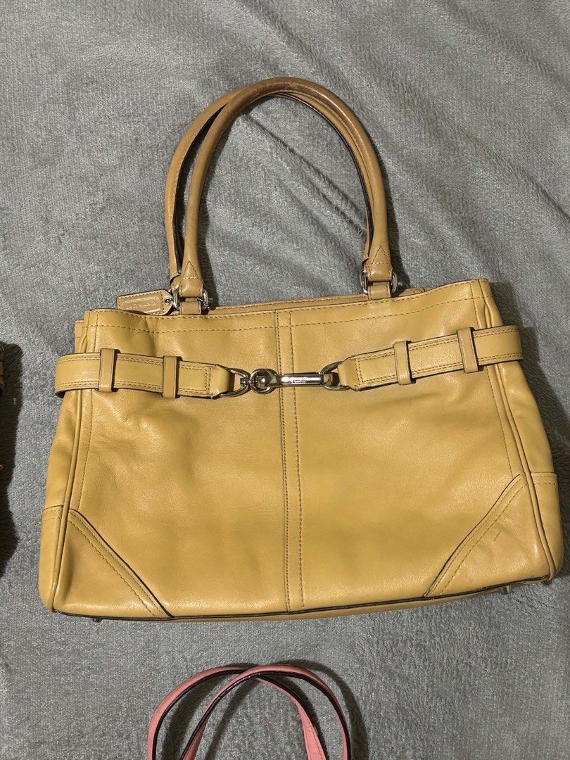 Coach Leather Tote Bag Yellow Tan (Category: Luxury Bags & Wallets) located in Taguig. Submitted by wonyjg (Listing ID 1466161531, Image 1). Description: Coach yellow leather tote bag with silver tone hardware and buckle strap detail across the front. Dual shoulder straps, protective metal feet on the bottom. Interior fabric lining includes a zippered pocket and slip pockets. Coach creed patch stamped inside with serial number. Classic structured