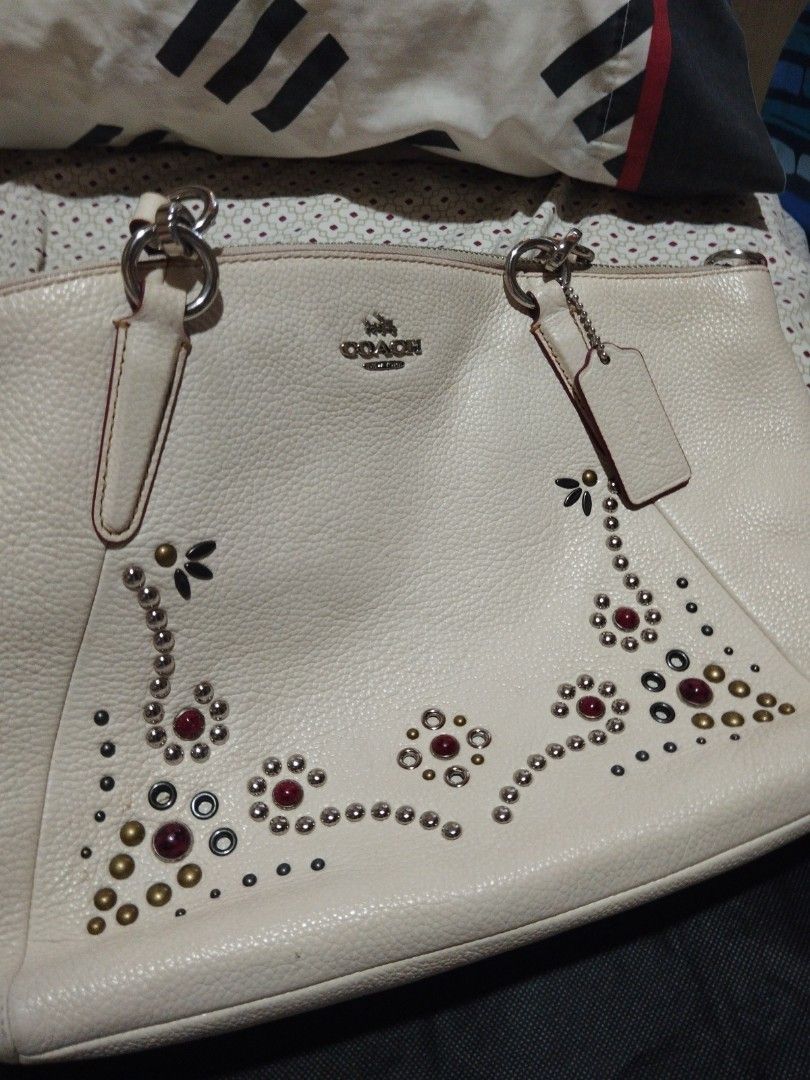 Coach White Leather Studded Handbag with Shoulder Strap (Category: Cross-body Bags) located in Manila. Submitted by lene48 (Listing ID 1466242461, Image 2). Description: - Brand: Coach - Material: White pebbled leather with silver-tone hardware - Design: Gorgeous floral studded and gemstone embellishments on the front, featuring the Coach horse and carriage logo - Handles & Strap: Dual rolled top handles with contrasting burgundy edging and a mat