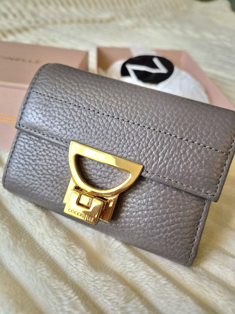 Coccinelle Trifold Leather Wallet with Box (Category: Wallets & Card holders) located in Paranaque City. Submitted by sampgm (Listing ID 1466208850, Image 1). Description: - Brand: Coccinelle - Material: Premium grey pebbled leather - Hardware: Gold-tone with signature clasp closure - Interior: Multiple card slots and secure zippered pocket - Inclusions: Original pink branded box and card - Condition: Well-maintained, minor scratches on hardware 