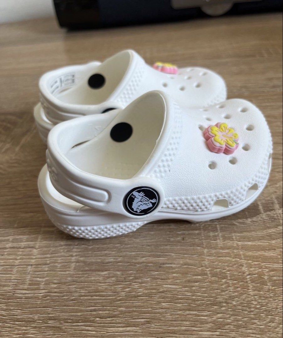 Crocs white c4 (Category: Babies & Kids Fashion) located in General Santos City (Dadiangas). Submitted by my_lzlove (Listing ID 1466336164, Image 1). Description: - Color: White with pink and yellow flower charms - Size: Toddler - Style: Easy slip-on with secure heel straps - Material: Lightweight foam - Best for: Playground, beach days, and everyday wear - Condition: Clean overall.