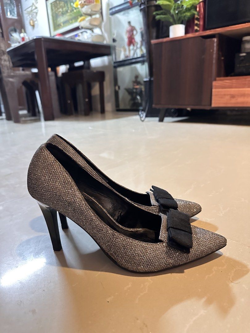 Daphne Silver Glitter Stiletto Heels with Bow (Category: Heels) located in Manila. Submitted by mysticdog_8e9243 (Listing ID 1466181154, Image 3). Description: - Brand/Model: Daphne Pointed-Toe Heels - Color: Sparkling silver with a contrasting black fabric bow on the front - Heel: Sleek stiletto with a black stiletto base - Sole: Textured underneath for better grip and slip resistance - Style: Classic slip-on pumps - Occasion: Ideal for parties,