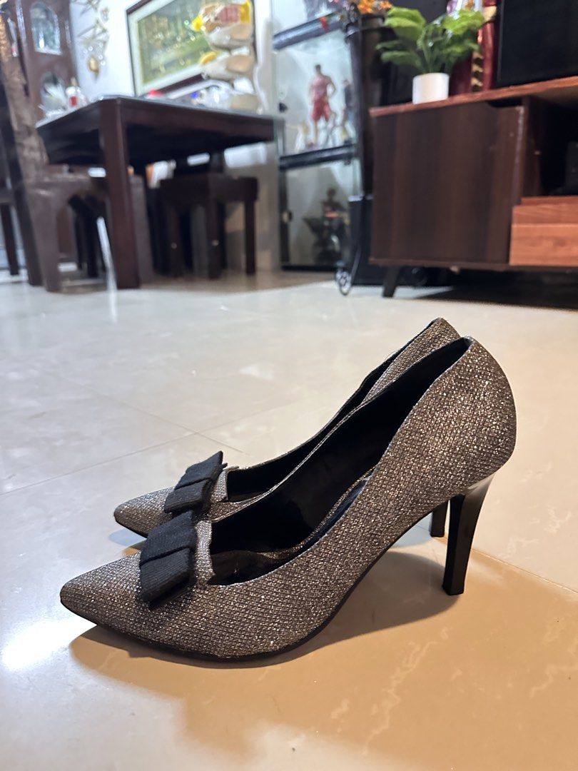Daphne Silver Glitter Stiletto Heels with Bow (Category: Heels) located in Manila. Submitted by mysticdog_8e9243 (Listing ID 1466181154, Image 1). Description: - Brand/Model: Daphne Pointed-Toe Heels - Color: Sparkling silver with a contrasting black fabric bow on the front - Heel: Sleek stiletto with a black stiletto base - Sole: Textured underneath for better grip and slip resistance - Style: Classic slip-on pumps - Occasion: Ideal for parties,