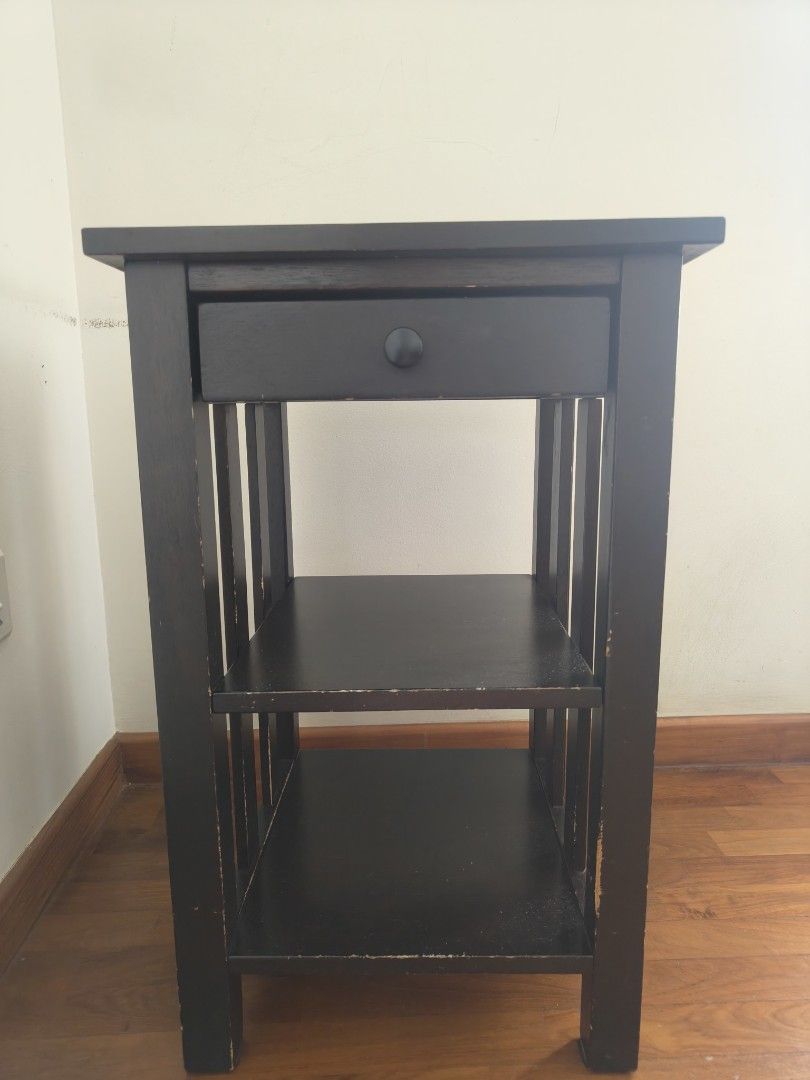 Side table (Category: Shelves, Cabinets & Racks) located in Singapore. Submitted by minml (Listing ID 1466201994, Image 1). Description: - Dark brown solid wood side table - 1 pull-out drawer with a black knob - 2 open lower shelves - Dimensions: height 61cm, 38cm x 38cm - side edges paint wear off. - pick up balestier/toa payoh.