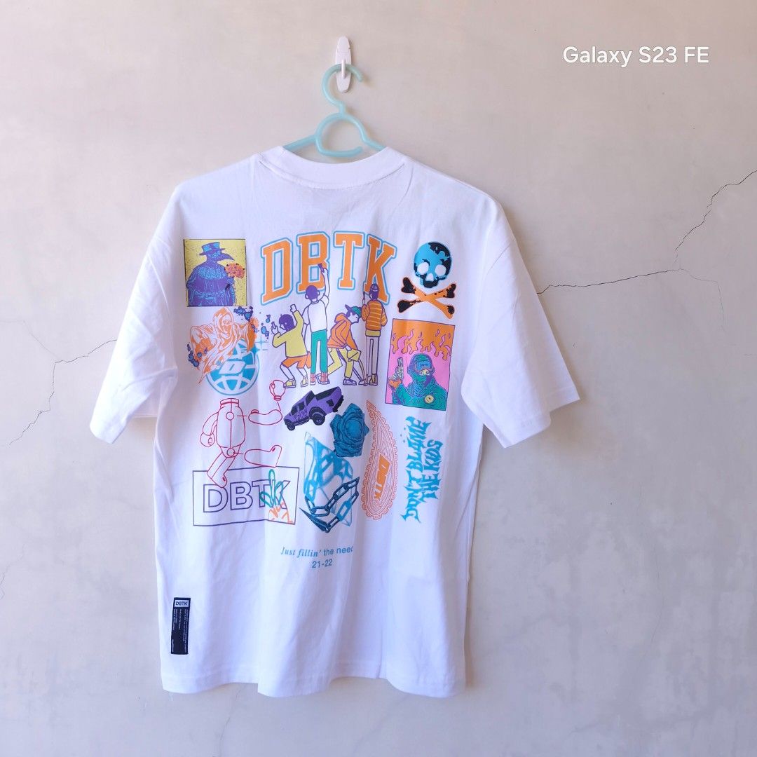 DBTK Graphic Tee White (Category: Tshirts & Polo Shirts ) located in Iloilo. Submitted by franzventures (Listing ID 1466179043, Image 2). Description: - Brand: DBTK (Don't Blame The Kids) - Color: Clean White - Design: Large front chest logo with a vibrant, detailed streetwear art and skull collage on the back - Fit: Short sleeves, crew neck - Style: Must-have streetwear piece.