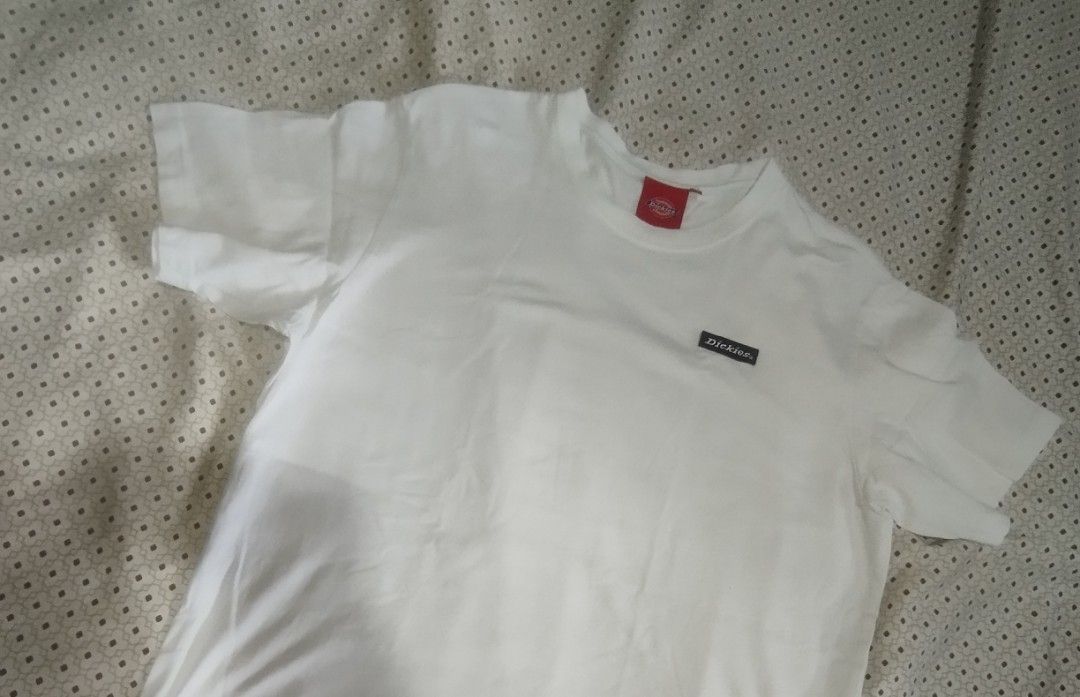 Dickies white t-shirt with chest logo patch (Category: Tshirts & Polo Shirts ) located in Manila. Submitted by lene48 (Listing ID 1466235933, Image 1). Description: - Brand: Dickies - Color: White - Style: Short-sleeve crew neck t-shirt - Details: Small embroidered black logo patch on left chest, iconic red Dickies flag tag near the hem, and classic red neck label - Condition: Clean, great for everyday wear.