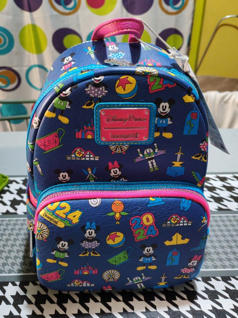 Disney Parks Loungefly Mini Backpack (Category: Babies & Kids Fashion) located in Makati City. Submitted by mccuachon (Listing ID 1466258766, Image 1). Description: - Authentic Disney Parks x Loungefly Disneyland 2024 mini backpack - Material: Blue faux leather with vibrant pink straps and handle - Design: All-over print featuring Mickey, Minnie, Tinker Bell, and Buzz Lightyear - Features: Bright blue zipper trim, front zipped pocket, and officia