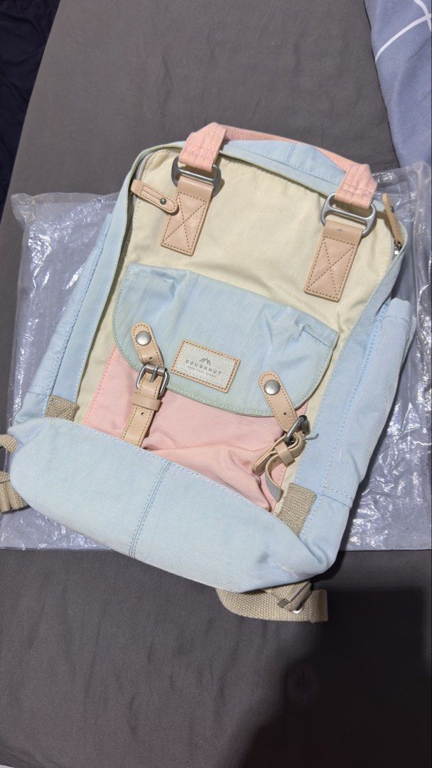 Doughnut Macaroon Pastel Pastel Color Backpack (Category: Backpacks) located in Cavite. Submitted by __elizagarcia.xi (Listing ID 1466201374, Image 2). Description: - Brand: Doughnut - Design: Pastel colorblock (light blue, soft pink, cream, beige) with genuine leather accents - Storage: Roomy main compartment, front buckle pocket, inside zipper mesh pocket, and inner slip pockets - Comfort & Carry: Double top carry handles and adjustable webbed 