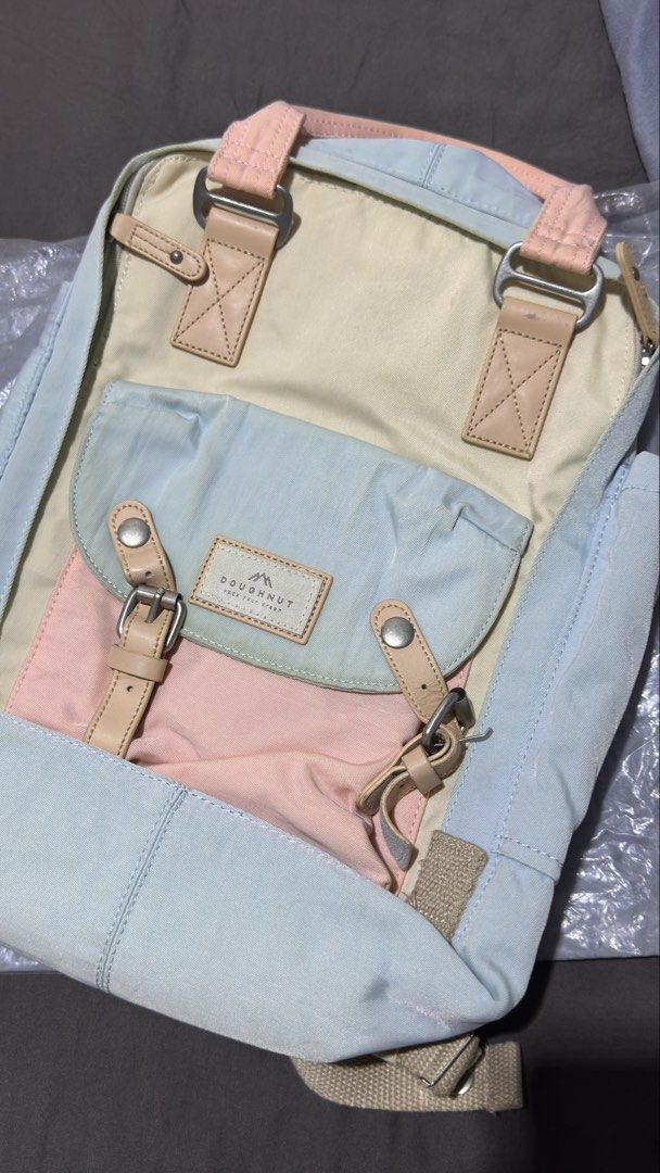 Doughnut Macaroon Pastel Pastel Color Backpack (Category: Backpacks) located in Cavite. Submitted by __elizagarcia.xi (Listing ID 1466201374, Image 1). Description: - Brand: Doughnut - Design: Pastel colorblock (light blue, soft pink, cream, beige) with genuine leather accents - Storage: Roomy main compartment, front buckle pocket, inside zipper mesh pocket, and inner slip pockets - Comfort & Carry: Double top carry handles and adjustable webbed 