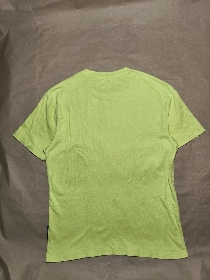 Evisu Lime Green Graphic T-Shirt (Category: Tshirts & Polo Shirts ) located in Manila. Submitted by thriftclothin (Listing ID 1466301726, Image 3). Description: - Brand: Evisu - Color: Bright lime green with a large purple graphic logo - Features: Short sleeves, crew neck, small branded black tag at the hem, Korean inner wash tag with QR code - Condition: Minor fabric wear and a faint stain near the lower left front graphic - Authentic streetwear