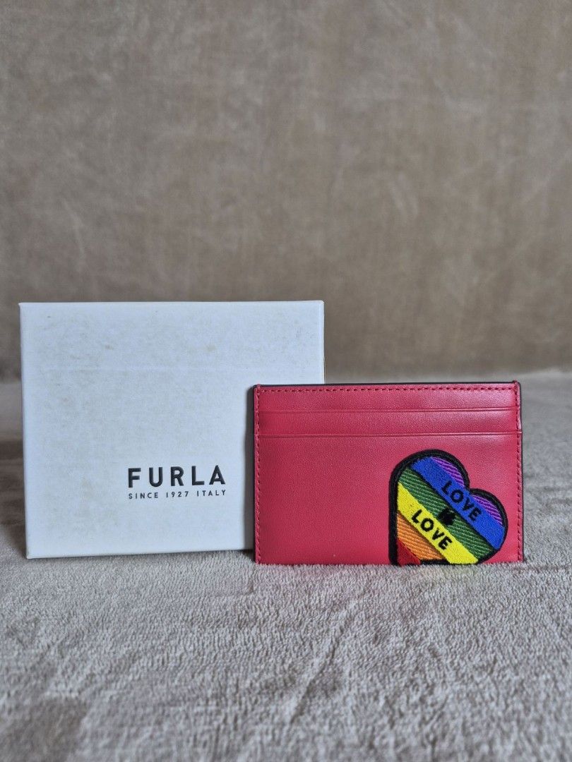 Furla Rainbow Heart Leather Card Holder (Category: Wallets & Card holders) located in Antipolo. Submitted by mfbien_ownpreloved (Listing ID 1466191713, Image 1). Description: Bright pink leather card holder by Furla. Features an embroidered rainbow heart patch on the front with "LOVE" . Multiple card slots on both sides. Silver-toned Furla logo stamped on the back. Includes original dust bag, tags, care booklet, and branded storage box. Price sli