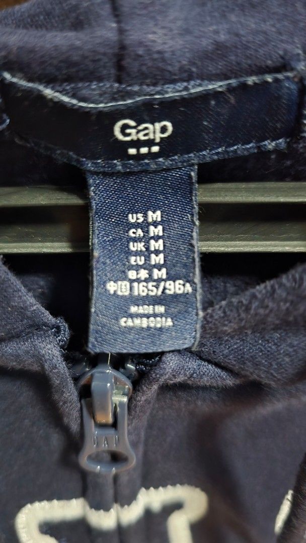 GAP Navy Blue Zip-Up Hoodie (Category: Coats, Jackets and Outerwear) located in Manila. Submitted by stuff.gaming (Listing ID 1466175958, Image 2). Description: - Brand: GAP - Style: Zip-up hoodie with classic front logo - Color: Navy blue - Size: Medium - Features: Front pockets and adjustable hood drawstrings - Condition: Clean, tags still attached.