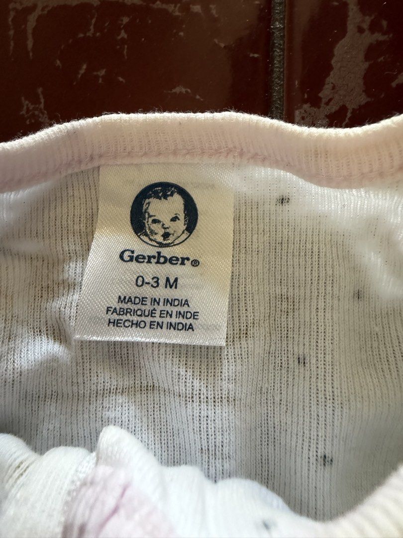 Gerber Baby Footed Sleeper Size 0-3M (Category: Babies & Kids Fashion) located in Las Pinas. Submitted by piwiealcantara (Listing ID 1466181675, Image 2). Description: - Brand: Gerber - Size: 0-3 Months - Design: White with gold crowns and tiny black dots, featuring cute pink trim - Features: Full zip front with protective top tab, long sleeves, and enclosed feet - Origin: Made in India - Condition: Clean, smoke-free, and ready to wear.