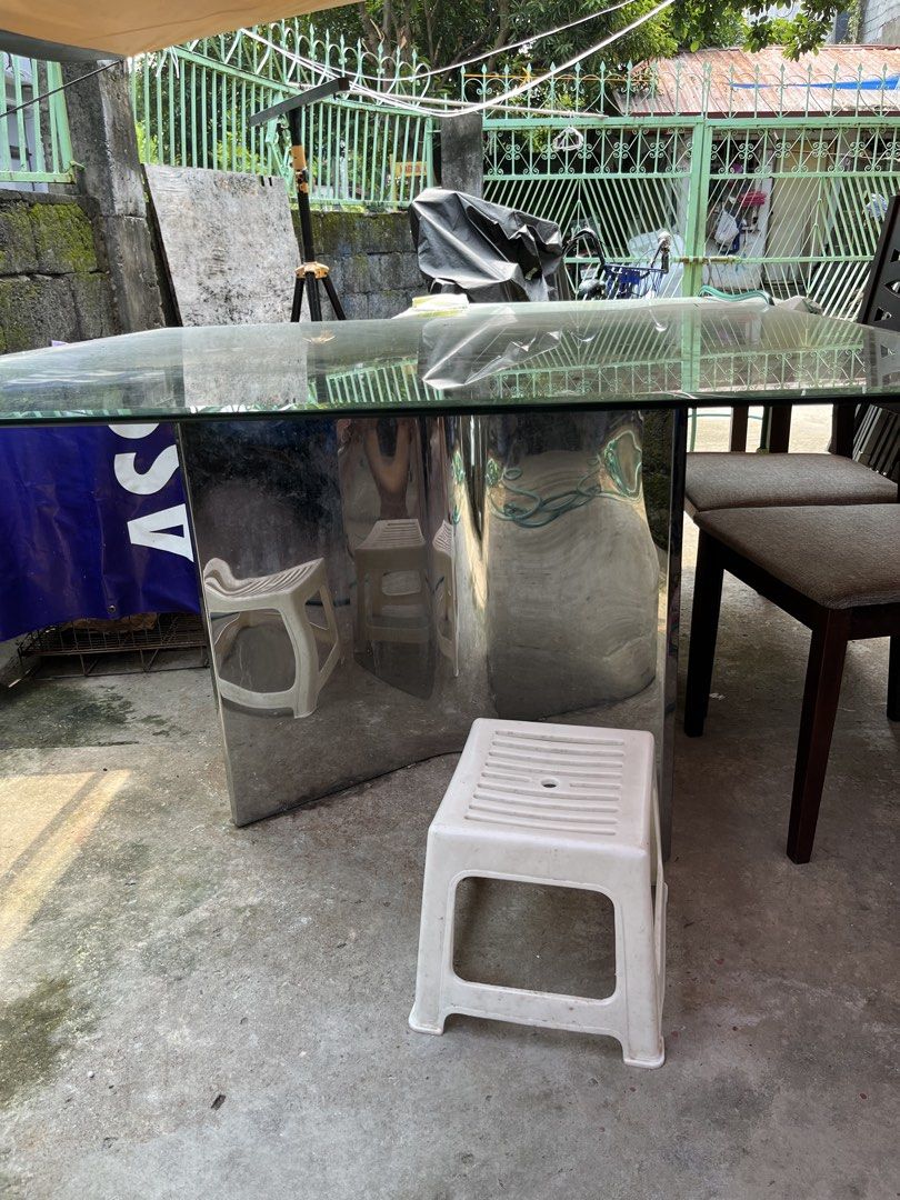 Glass top dining table with chrome base (Category: Tables & Sets) located in Manila. Submitted by sabrinaa20 (Listing ID 1466254679, Image 2). Description: - Modern square dining table - Thick glass top with normal surface wear (no cracks) - Shiny chrome metal pedestal base - Seats 8 comfortably - Sturdy, heavy build for maximum stability - Pick up only (due to size and weight).