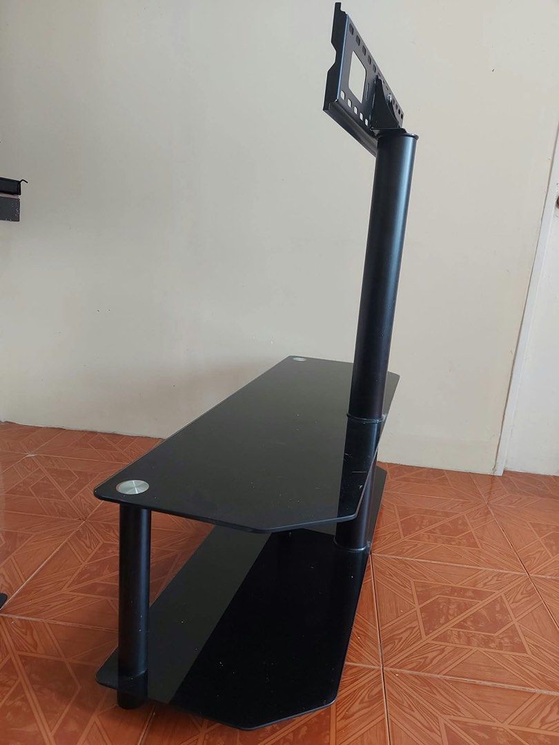 Glass TV Stand with Integrated Mount (Category: TV Consoles) located in Binan City. Submitted by zklge (Listing ID 1466312444, Image 2). Description: - Modern black glass TV stand with a built-in mounting bracket - Sturdy solid steel pole for secure TV mounting - Two tempered glass shelves for consoles, cable boxes, or soundbars - Clean and minimalist setup ideal for living rooms or bedrooms - Easy to disassemble for convenient transport and pick