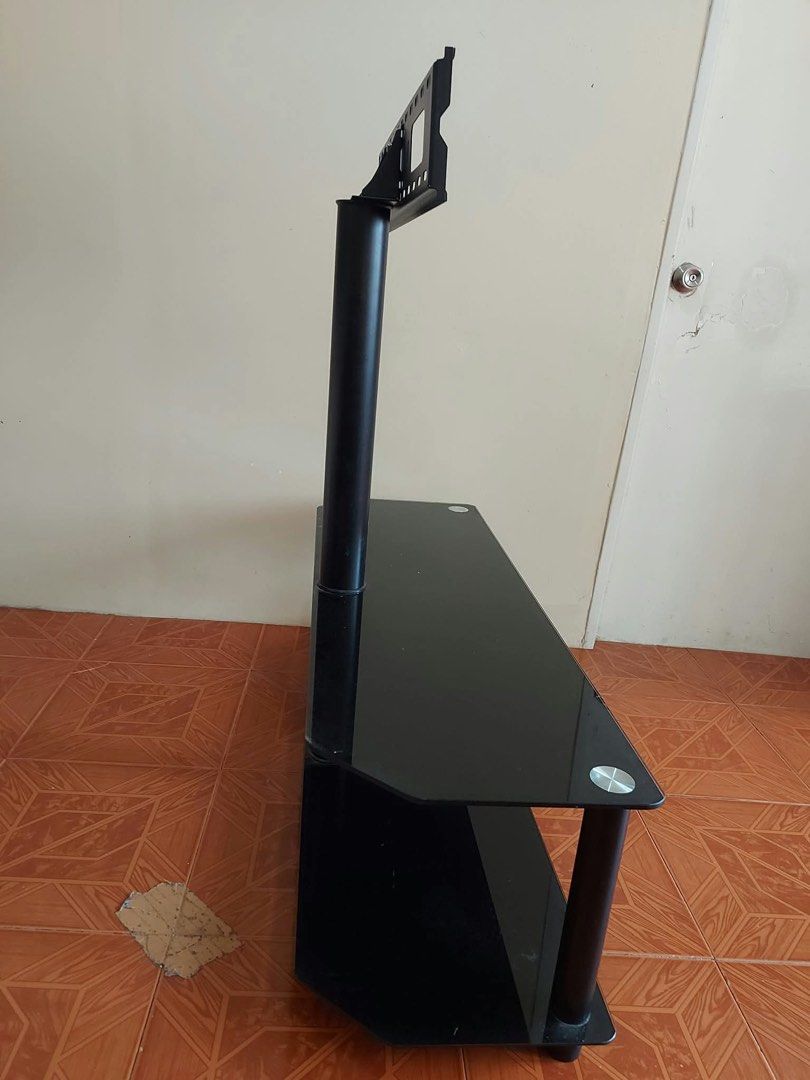Glass TV Stand with Integrated Mount (Category: TV Consoles) located in Binan City. Submitted by zklge (Listing ID 1466312444, Image 3). Description: - Modern black glass TV stand with a built-in mounting bracket - Sturdy solid steel pole for secure TV mounting - Two tempered glass shelves for consoles, cable boxes, or soundbars - Clean and minimalist setup ideal for living rooms or bedrooms - Easy to disassemble for convenient transport and pick