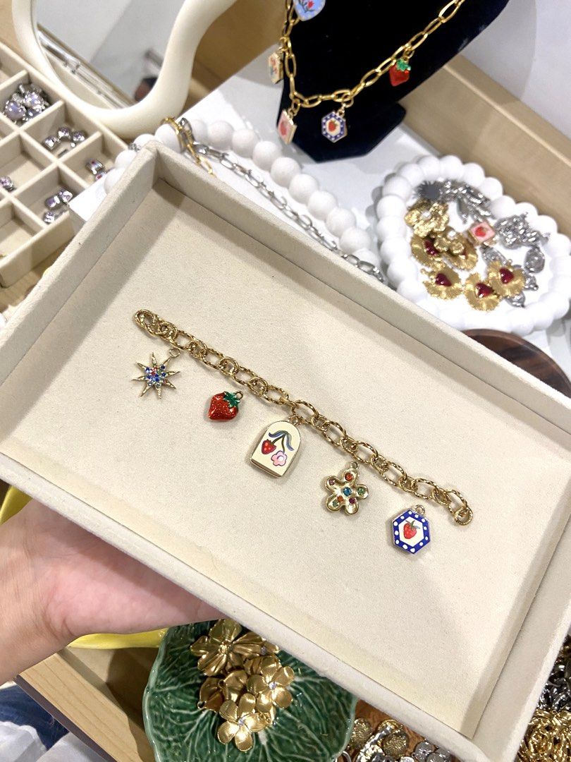 Gold Charm Bracelet (Category: Bracelets) located in Manila. Submitted by pandaaa_loo (Listing ID 1466272821, Image 1). Description: - Gold-tone chain link bracelet - Cute charms: strawberries, gem flowers, sunburst crystal star, and enamel floral pendants - Solid and chunky links with a secure clasp - Perfect for everyday wear or stacking with other accessories.