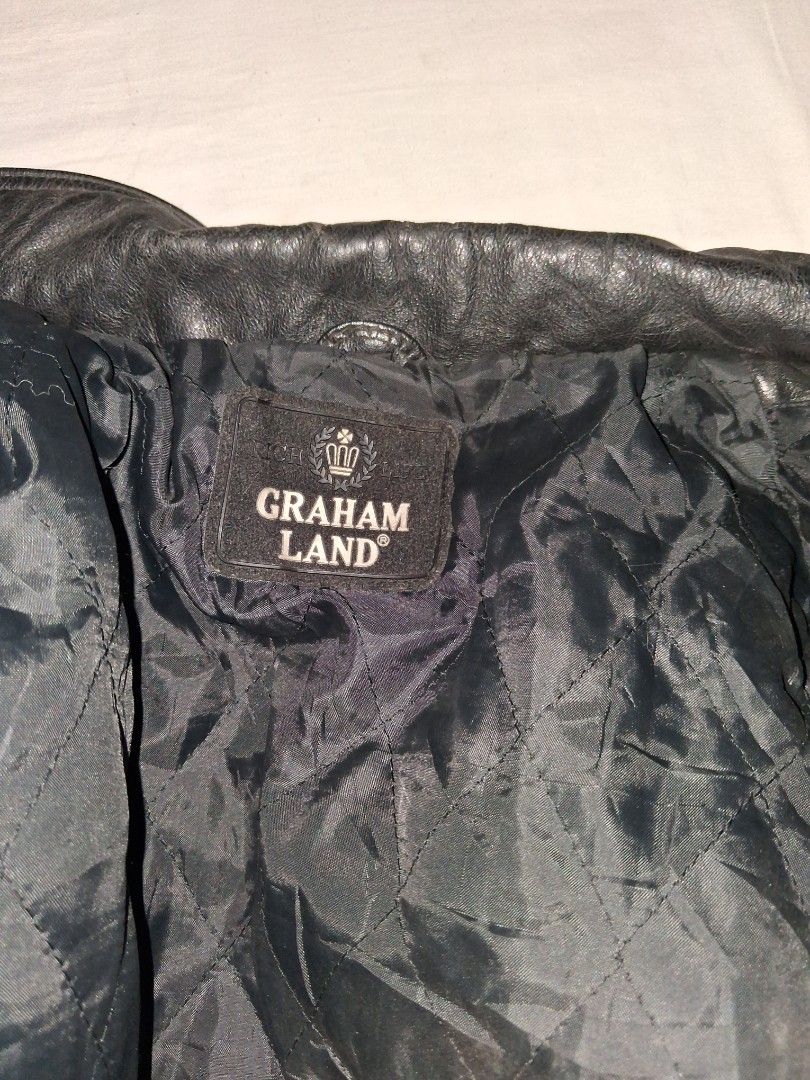 Graham Land Black Leather Jacket (Category: Coats, Jackets and Outerwear) located in Manila. Submitted by marcas022798212 (Listing ID 1466164659, Image 2). Description: - Brand: Graham Land - Color: Black - Material: Rugged textured leather with a warm quilted black inner lining - Closure: Zip-up front with additional button detail - Pockets: Convenient front pockets included - Size: 23x30 (based on measurement tape in photos) - Condition: Excell