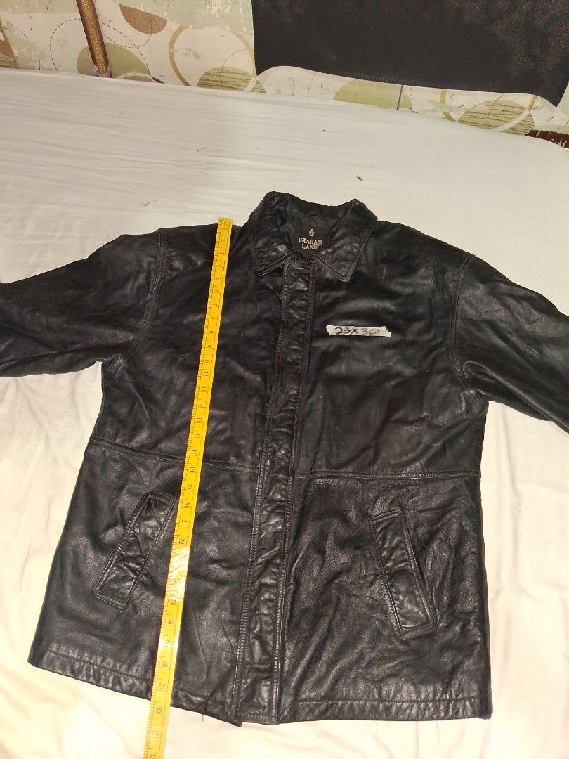 Graham Land Black Leather Jacket (Category: Coats, Jackets and Outerwear) located in Manila. Submitted by marcas022798212 (Listing ID 1466164659, Image 1). Description: - Brand: Graham Land - Color: Black - Material: Rugged textured leather with a warm quilted black inner lining - Closure: Zip-up front with additional button detail - Pockets: Convenient front pockets included - Size: 23x30 (based on measurement tape in photos) - Condition: Excell