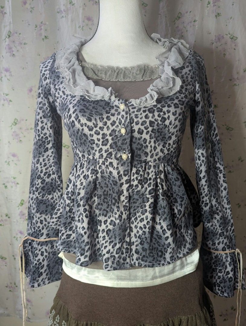Grey Leopard Print Ruffle Cardigan Top (Category: Coats, Jackets and Outerwear) located in Manila. Submitted by drei_thrift (Listing ID 1466197950, Image 1). Description: - Grey and white leopard print - Long sleeves with adjustable tie cuffs - Ruffle trim wide neckline - Button-up front with pearl buttons - Flared peplum waist silhouette - Soft, lightweight knit material.