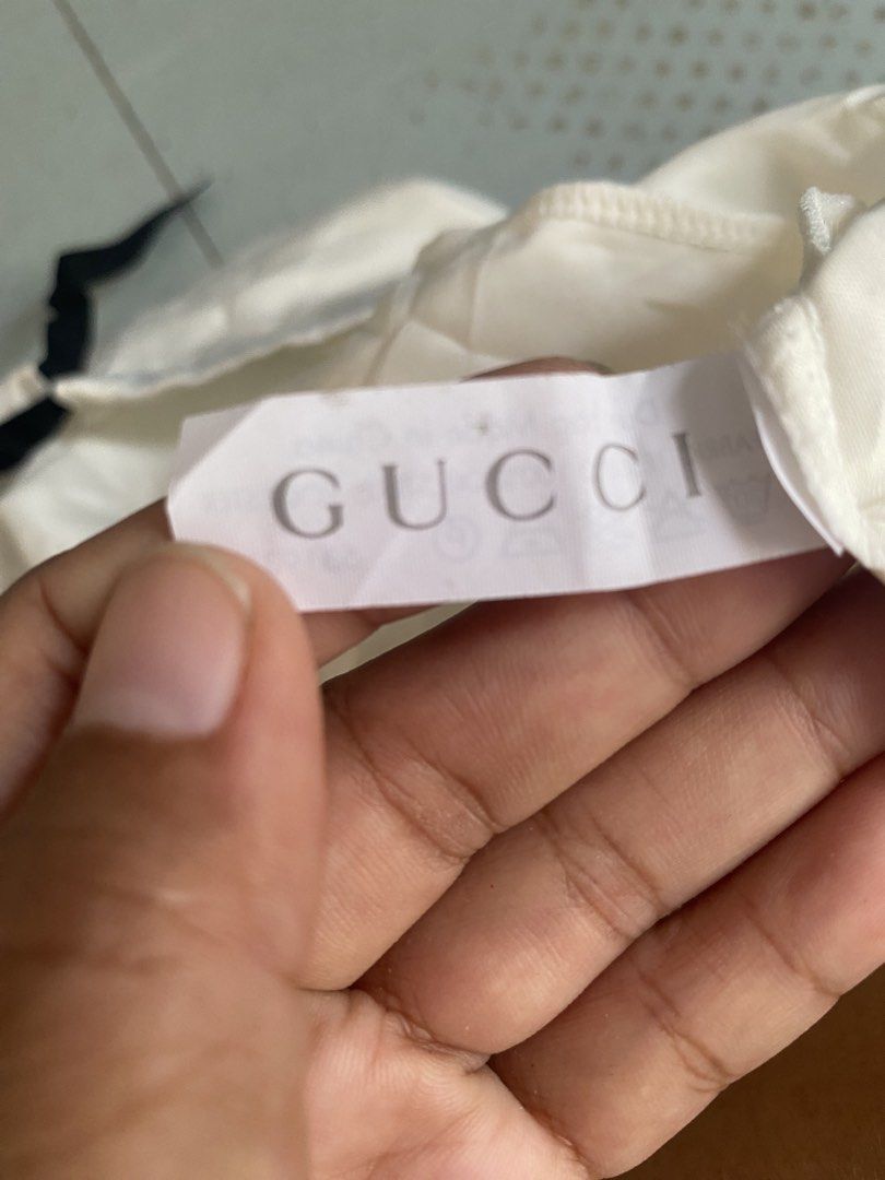 Gucci Dust Bag White Cotton (Category: Luxury Bags & Wallets) located in Davao. Submitted by dandeshop (Listing ID 1466217123, Image 2). Description: - Authentic white Gucci dust bag - Secure top drawstring closure - Features inner fabric label with Gucci lettering and care instructions - Features rectangular Gucci logo label near the bottom - Clean condition overall with minor wrinkles from storage.