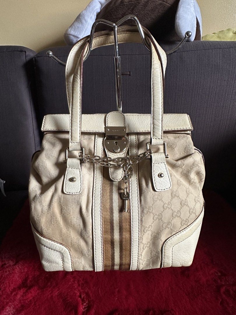 Gucci GG Canvas Web Stripe Padlock Tote Handbag (Category: Luxury Bags & Wallets) located in Quezon City. Submitted by shopaholic.kart2021 (Listing ID 1466228575, Image 1). Description: Beige and white Gucci handbag with GG monogram canvas and brown web stripe down the center. Silver-tone hardware includes a front lock closure with hanging key and chain detail. Cream leather trim and dual top handles. Interior features a zippered pocket and leath