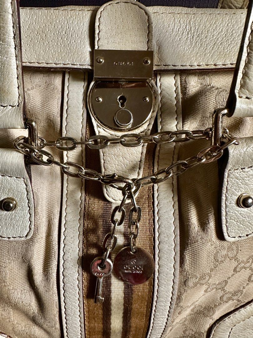 Gucci GG Canvas Web Stripe Padlock Tote Handbag (Category: Luxury Bags & Wallets) located in Quezon City. Submitted by shopaholic.kart2021 (Listing ID 1466228575, Image 3). Description: Beige and white Gucci handbag with GG monogram canvas and brown web stripe down the center. Silver-tone hardware includes a front lock closure with hanging key and chain detail. Cream leather trim and dual top handles. Interior features a zippered pocket and leath