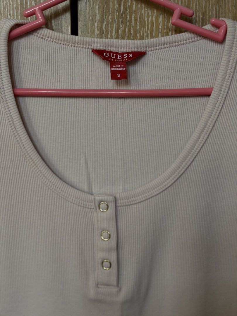Guess Pink Ribbed Henley Tee Size S (Category: Shirts) located in Las Pinas. Submitted by chybautista (Listing ID 1466168293, Image 3). Description: Guess ribbed henley top in light pink. Chest 32-34 Length - 22 Stretch Scoop neckline with three metallic snap buttons. Short sleeves and slim fit cut. Small gold tone Guess logo plaque near the bottom hem. Soft cotton blend material. Size small tag attached inside. Clean condition with no stains or 