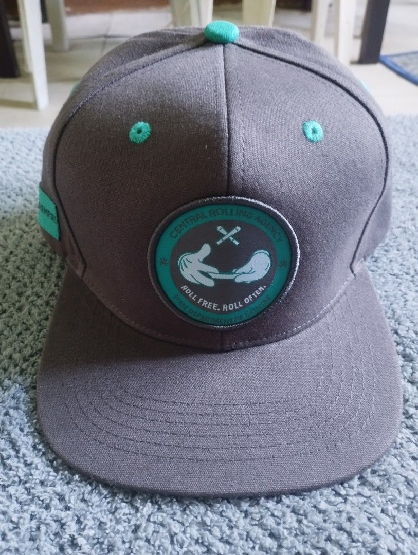 Hempire Snapback Hat Gray Teal (Category: Caps & Hats) located in Manila. Submitted by happycaps (Listing ID 1466172526, Image 1). Description: - Brand: Hempire - Style: Gray snapback cap with adjustable snap closure - Design: Central Rolling Agency patch on the front with cartoon hands rolling a joint - Details: Eye-catching teal eyelets, top button, strap, underbrim, and side tag - Interior: Branded taped seams and a green weed leaf pattern lin