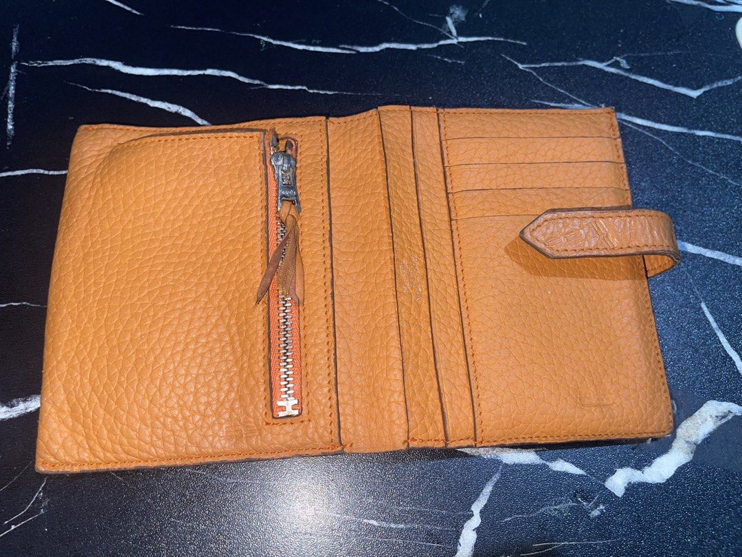 Hermes Orange Leather Compact Wallet (Category: Wallets & Card holders) located in Manila. Submitted by preloveditems_jem (Listing ID 1466253904, Image 1). Description: Authentic Hermes bi-fold wallet in iconic bright orange grained leather. Features a silver-toned zip pocket, multiple card slots, and a secure snap-tab closure. Shows very minor signs of gentle use. A gorgeous pop of color for your everyday essentials!.