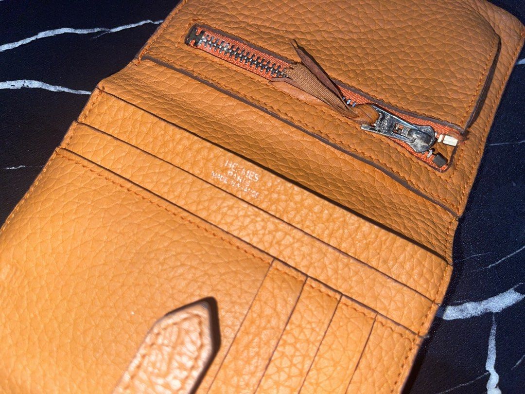 Hermes Orange Leather Compact Wallet (Category: Wallets & Card holders) located in Manila. Submitted by preloveditems_jem (Listing ID 1466253904, Image 2). Description: Authentic Hermes bi-fold wallet in iconic bright orange grained leather. Features a silver-toned zip pocket, multiple card slots, and a secure snap-tab closure. Shows very minor signs of gentle use. A gorgeous pop of color for your everyday essentials!.