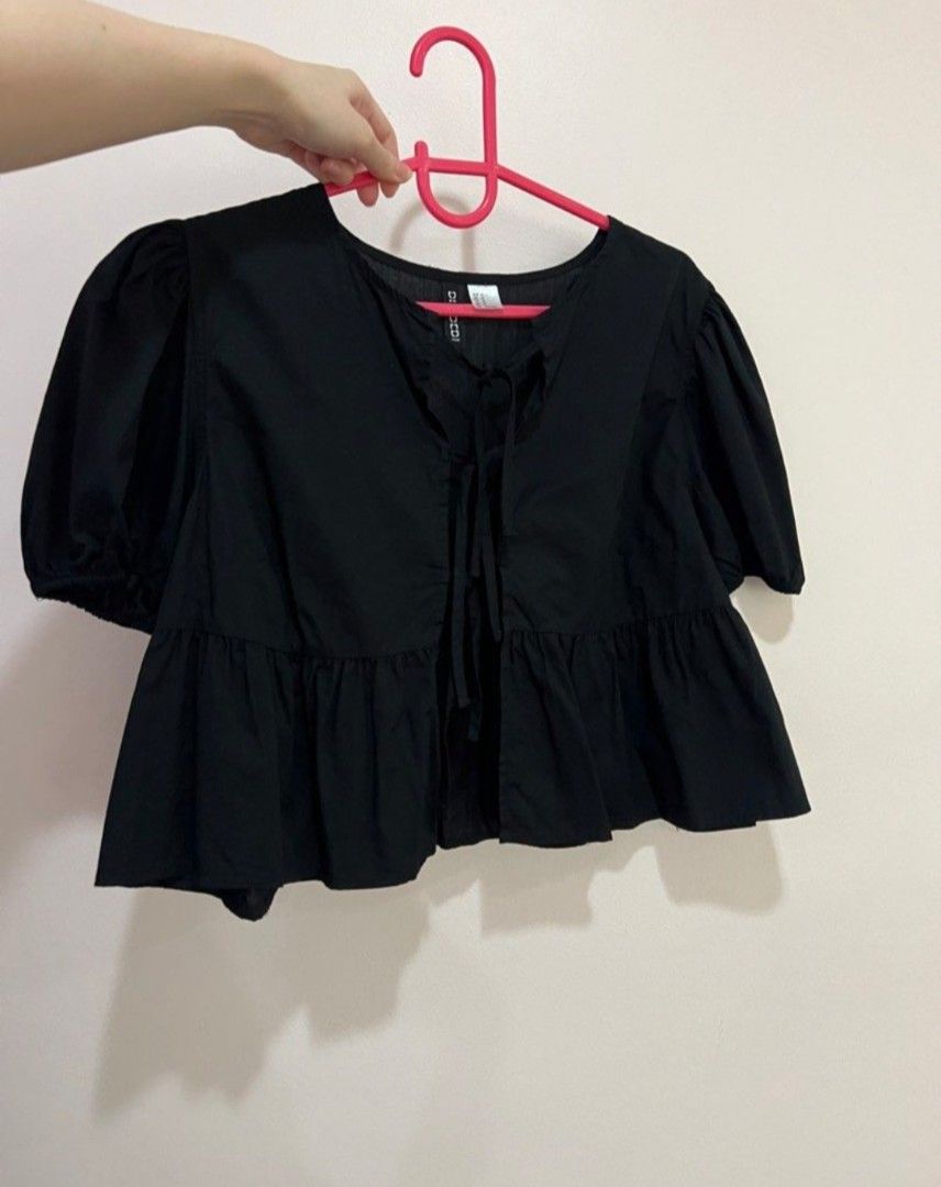 H&M Black Tie-Front Peplum Blouse (Category: Blouses) located in San Carlos. Submitted by my.excess.stuff (Listing ID 1466335771, Image 2). Description: - Brand: H&M - Color: Black - Style: Short-sleeve top with puff sleeves and tie-front ribbon closure - Details: Flared peplum hem for extra texture - Material: Lightweight cotton - Best paired with: High-waisted jeans for a casual day out.