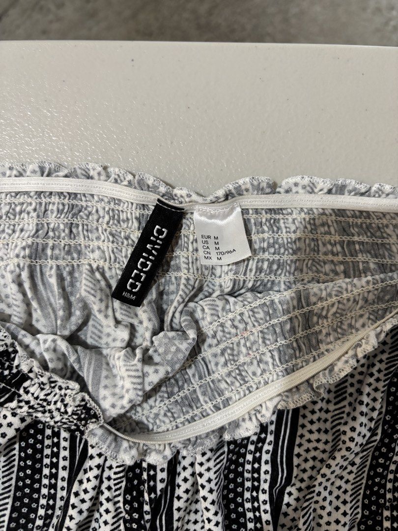 H&M Divided Black and White Patterned Off-Shoulder Blouse (Category: Blouses) located in Guimba. Submitted by huenited (Listing ID 1466215459, Image 2). Description: - Brand: H&M Divided - Size: Medium - Style: Off-shoulder top with long sleeves - Design: Black and white vertical stripes with small geometric prints - Fit: Smocked elastic at top and hem for extra stretch and comfort - Condition: Pre-loved, well-maintained.