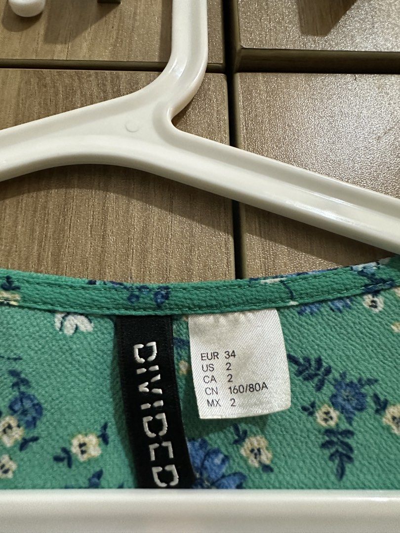 H&M Divided Floral Wrap Peplum Top (Category: Blouses) located in Quezon City. Submitted by sofieegee (Listing ID 1466294023, Image 2). Description: - Brand: Divided by H&M - Size: EUR 34 / US 2 - Design: Green with blue and white floral print, V-neck wrap front - Details: Ruffled bell sleeves and peplum hem - Material: Light and comfortable fabric - Versatile: Perfect for casual outings or office wear.