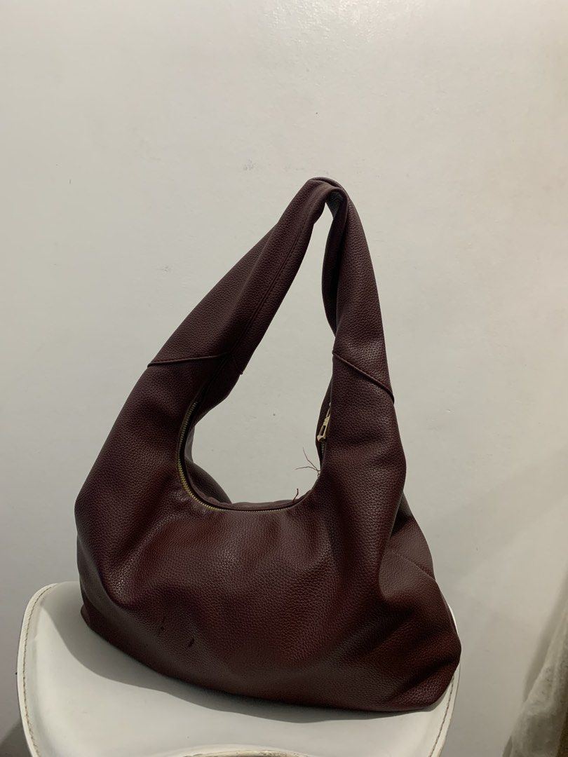 Hobo Bag (Category: Shoulder Bags) located in Manila. Submitted by seasalt.000 (Listing ID 1466286297, Image 1). Description: - Color & Material: Rich maroon faux leather with a soft pebbled texture - Style: Slouchy hobo shoulder bag with a curved gold-tone zipper closure - Capacity: Spacious interior, perfect for daily use - Condition: Pre-loved with minor scuffs near the base and some loose threads near the zipper track.