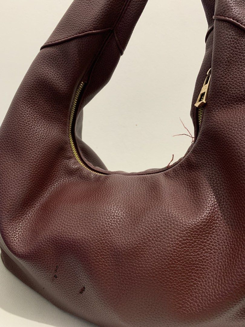 Hobo Bag (Category: Shoulder Bags) located in Manila. Submitted by seasalt.000 (Listing ID 1466286297, Image 2). Description: - Color & Material: Rich maroon faux leather with a soft pebbled texture - Style: Slouchy hobo shoulder bag with a curved gold-tone zipper closure - Capacity: Spacious interior, perfect for daily use - Condition: Pre-loved with minor scuffs near the base and some loose threads near the zipper track.