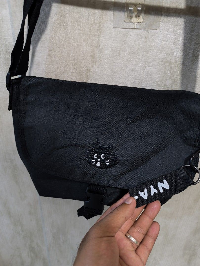 ISSEY MIYAKE NE-NET SLING BAG (Category: Cross-body Bags) located in Santiago. Submitted by dc_daily_thrift (Listing ID 1466310093, Image 3). Description: - ISSEY MIYAKE NE-NET SLING BAG - Color: Classic Black - Material: Durable and clean canvas - Features: Cute embroidered cat face patch and front buckle closure - Strap: Adjustable for comfortable wear - Storage: Handy back slip pocket and main compartment fits phone, wallet, and essentials - E