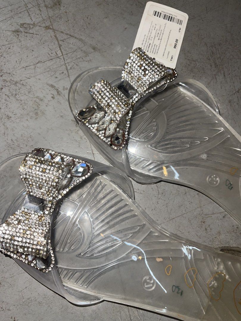 Jelly Bunny Clear Rhinestone Bow Flat Sandals (Category: Flats & Sandals) located in La Trinidad. Submitted by potatothriftlip (Listing ID 1466238981, Image 2). Description: Clear jelly sandals from Jelly Bunny. Rhinestone encrusted bow on the front strap. Heel area fully covered in tiny sparkling crystals. Slip-on design with transparent sole and heart graphics printed inside. Size 38 marked on the insole. Original store tag attached with price 