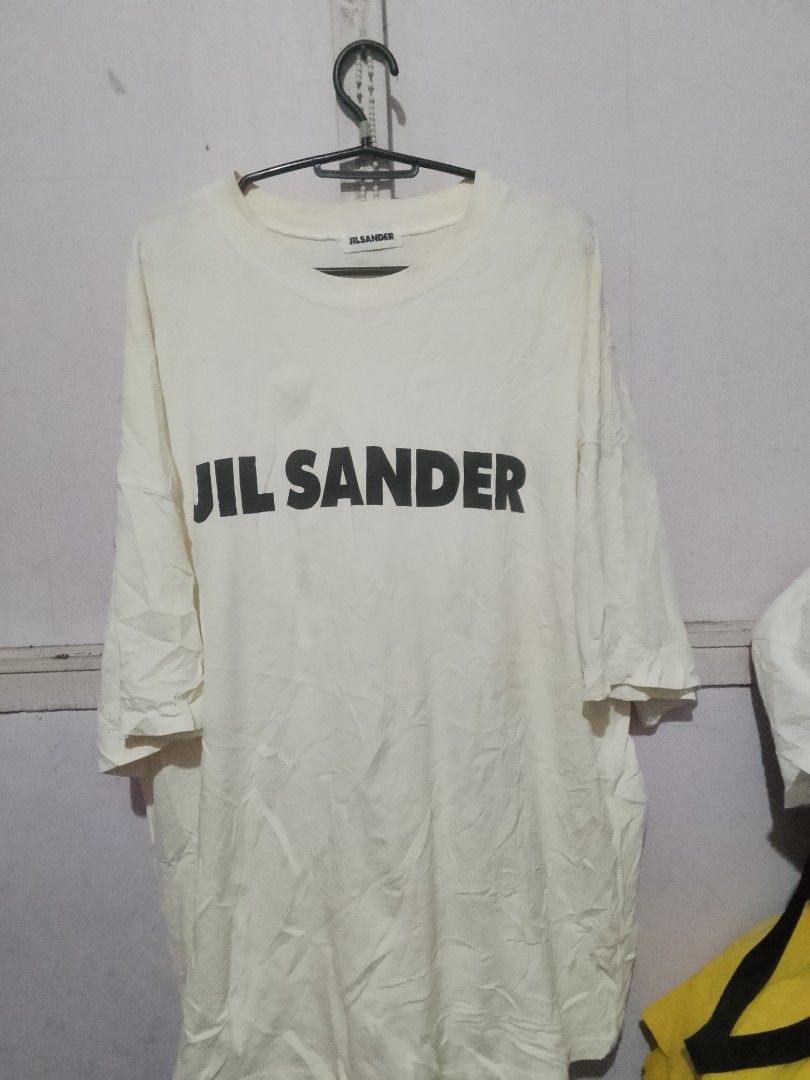 Jil Sander Logo Print White T-Shirt (Category: Activewear) located in Quezon City. Submitted by theoneshop1 (Listing ID 1466258768, Image 1). Description: - Brand: Jil Sander - Color: Off-white with bold black chest lettering - Size: Large (relaxed, oversized fit) - Material: 100% premium cotton - Details: Crew neckline, short sleeves, Made in Italy interior label - Condition: Brand new/Mint (ready to wear).