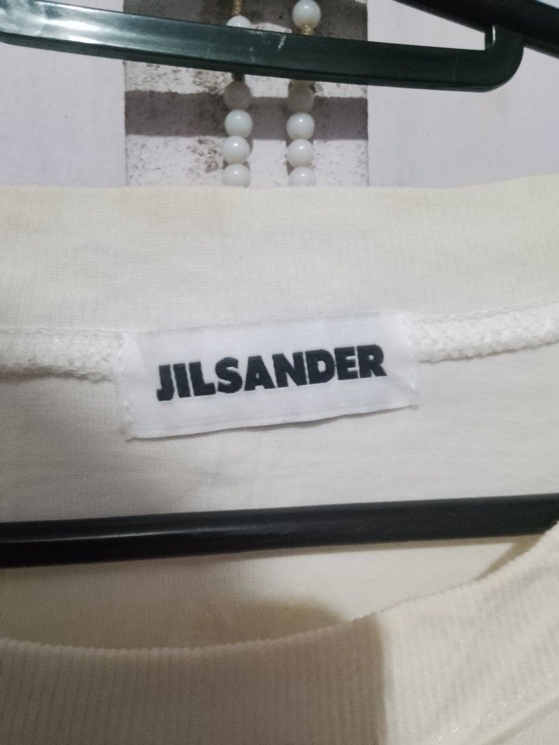 Jil Sander Logo Print White T-Shirt (Category: Activewear) located in Quezon City. Submitted by theoneshop1 (Listing ID 1466258768, Image 2). Description: - Brand: Jil Sander - Color: Off-white with bold black chest lettering - Size: Large (relaxed, oversized fit) - Material: 100% premium cotton - Details: Crew neckline, short sleeves, Made in Italy interior label - Condition: Brand new/Mint (ready to wear).